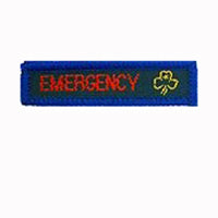 blue rectangle woven badge with the word emergency sewn in red in capital letters and a gold trefoil after the writing