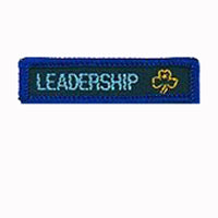 blue rectangle woven badge with the word leadership sewn in light blue in capital letters and a gold trefoil after the writing