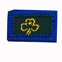 square blue woven badge with gold trefoil in the middle