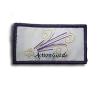 rectangular cloth bound badge with purple trim around the edges, trefoil in gold, Action Guide written in black and stripes of purple and gold on a white background