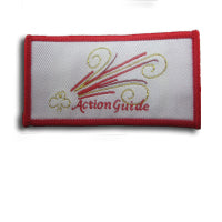 rectangular cloth bound badge with red trim , trefoil in gold, Action Guide written in red and stripes of red and gold on a white background
