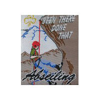 unbound fun badge with a gold trefoil and a picture of a girl abseiling down a rock face