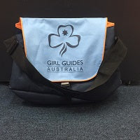 over the shoulder bag with a clip front, navy blue with a light blue front flap with the trefoil and girl guides Australia printed on it in dark blue