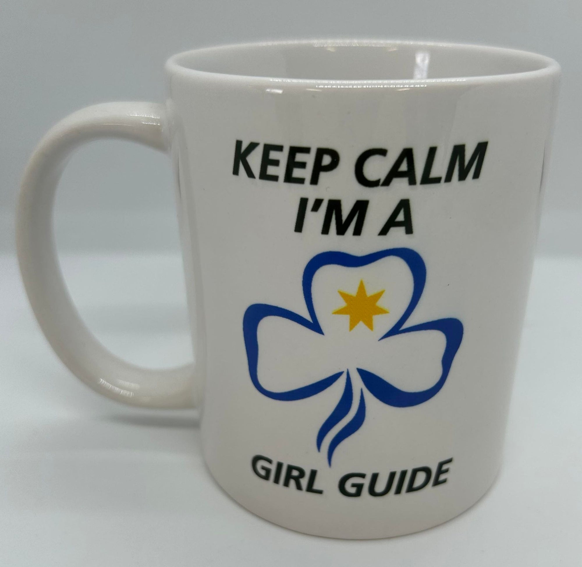 a white coffee cup with a picture of the CVR badge on one side and a trefoil and keep calm I'm a girl guide on the other side
