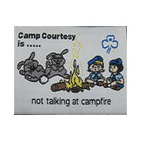 Unbound fun badge. Words read Camp Courtesy is not talking at campfire. Embroidered picture of two Guides and two rabbits sitting around a campfire on a white background.