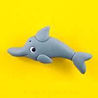 Grey clay badge in shape of dolphin