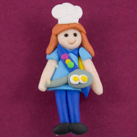 handmade clay brooch of a guide with a chefs hat and a fry pan with eggs in it