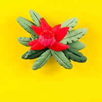 Clay badge in detailed shape of waratah - coloured red and green