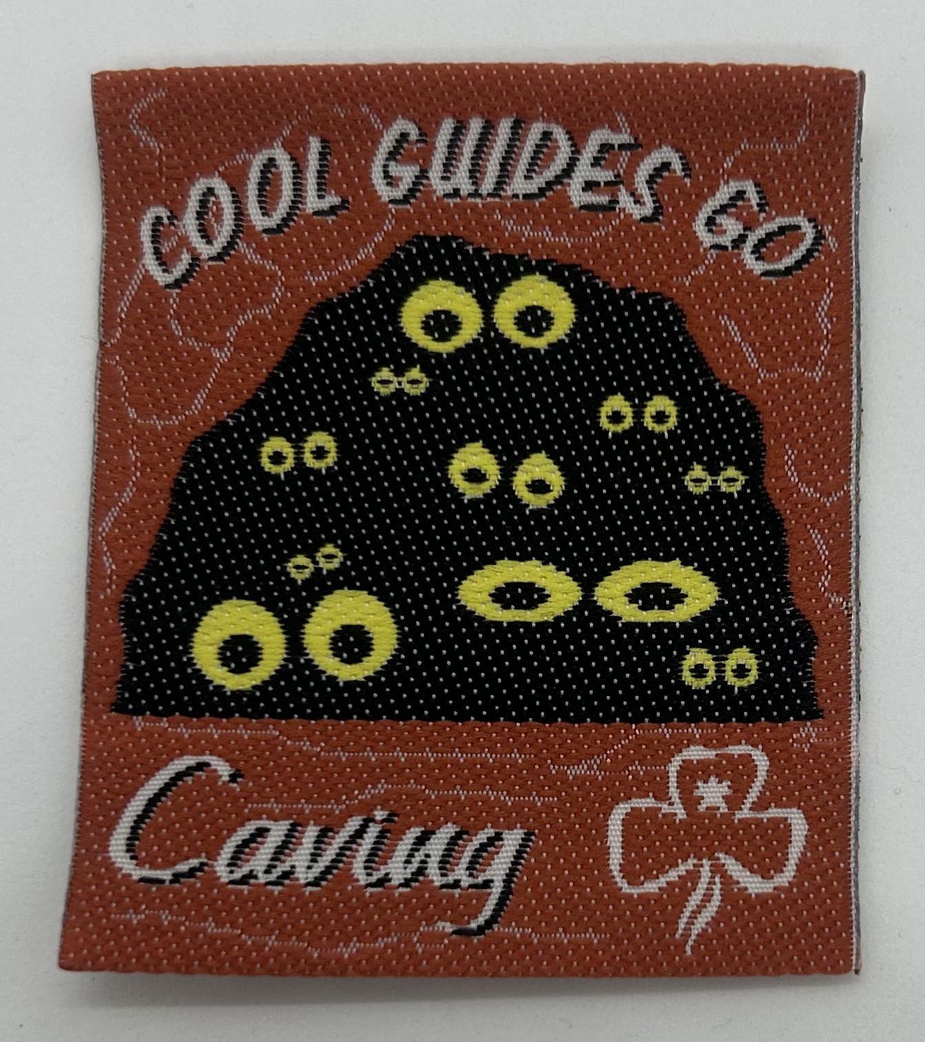 a square unbound fun badge badge with a dark cave with yellow eyes inside 