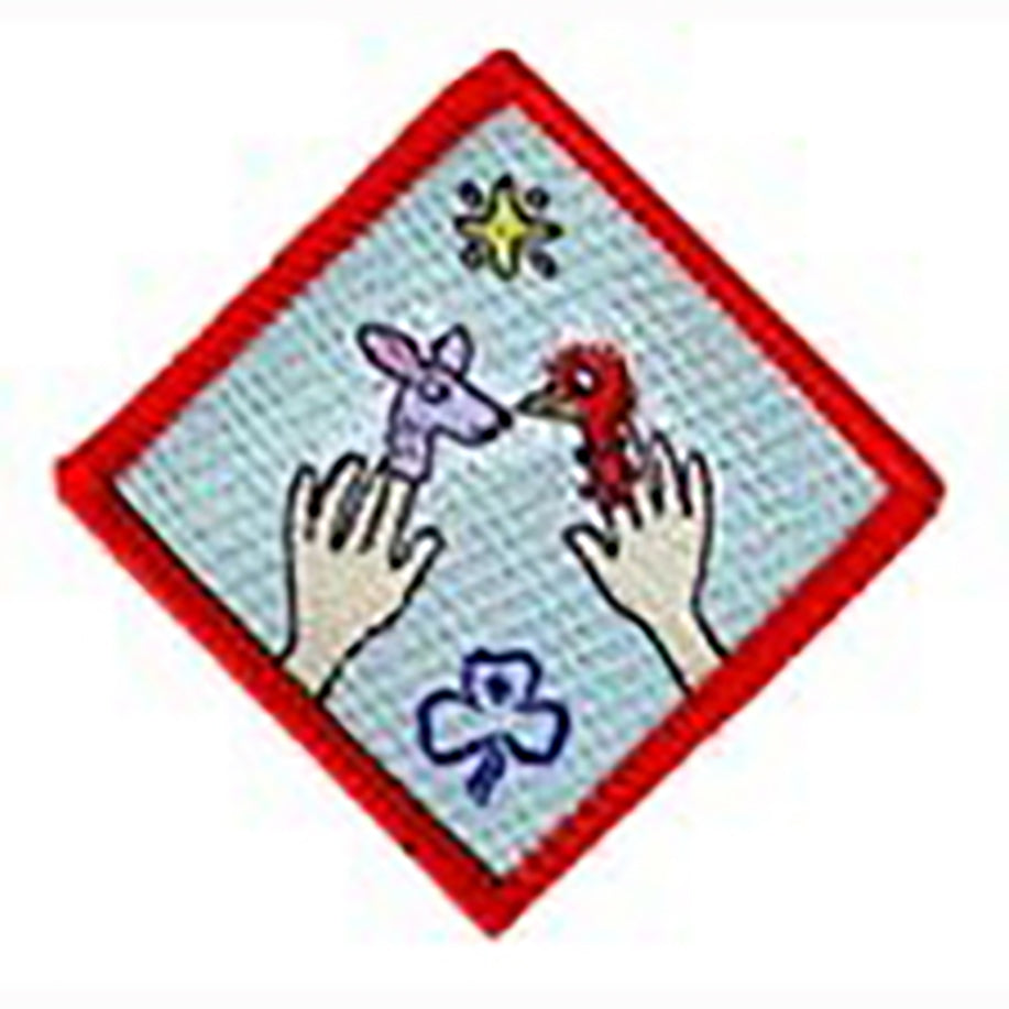 diamond shaped badge bound in red with two hands with finger puppets on a blue back ground