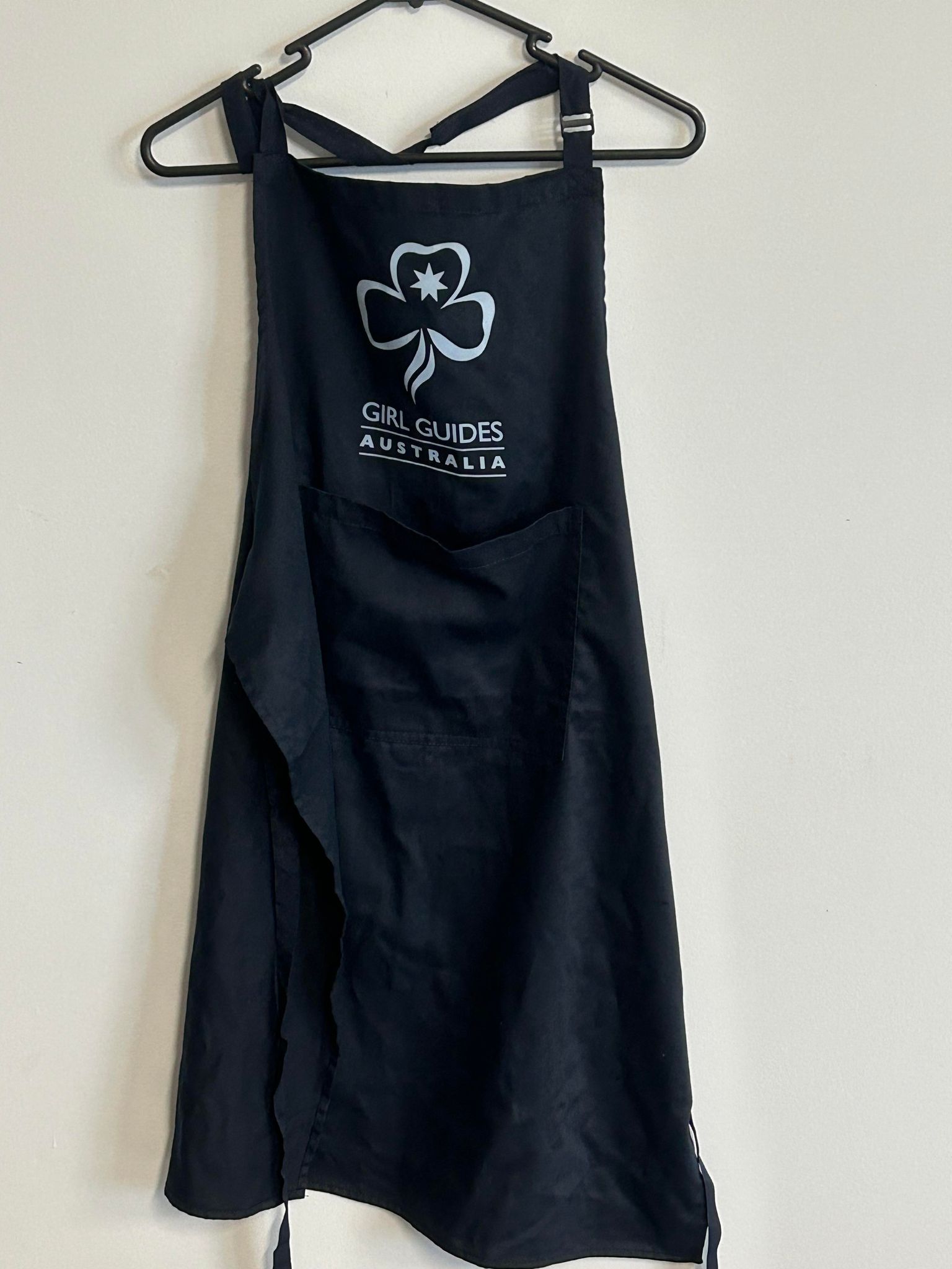 a navy blue apron with a trefoil and girl guides Australia on the front