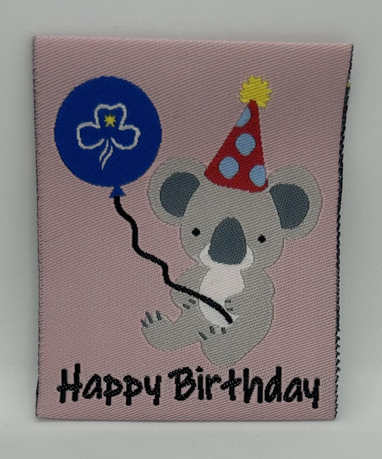 a square unbound pink badge with a koala holding a balloon
