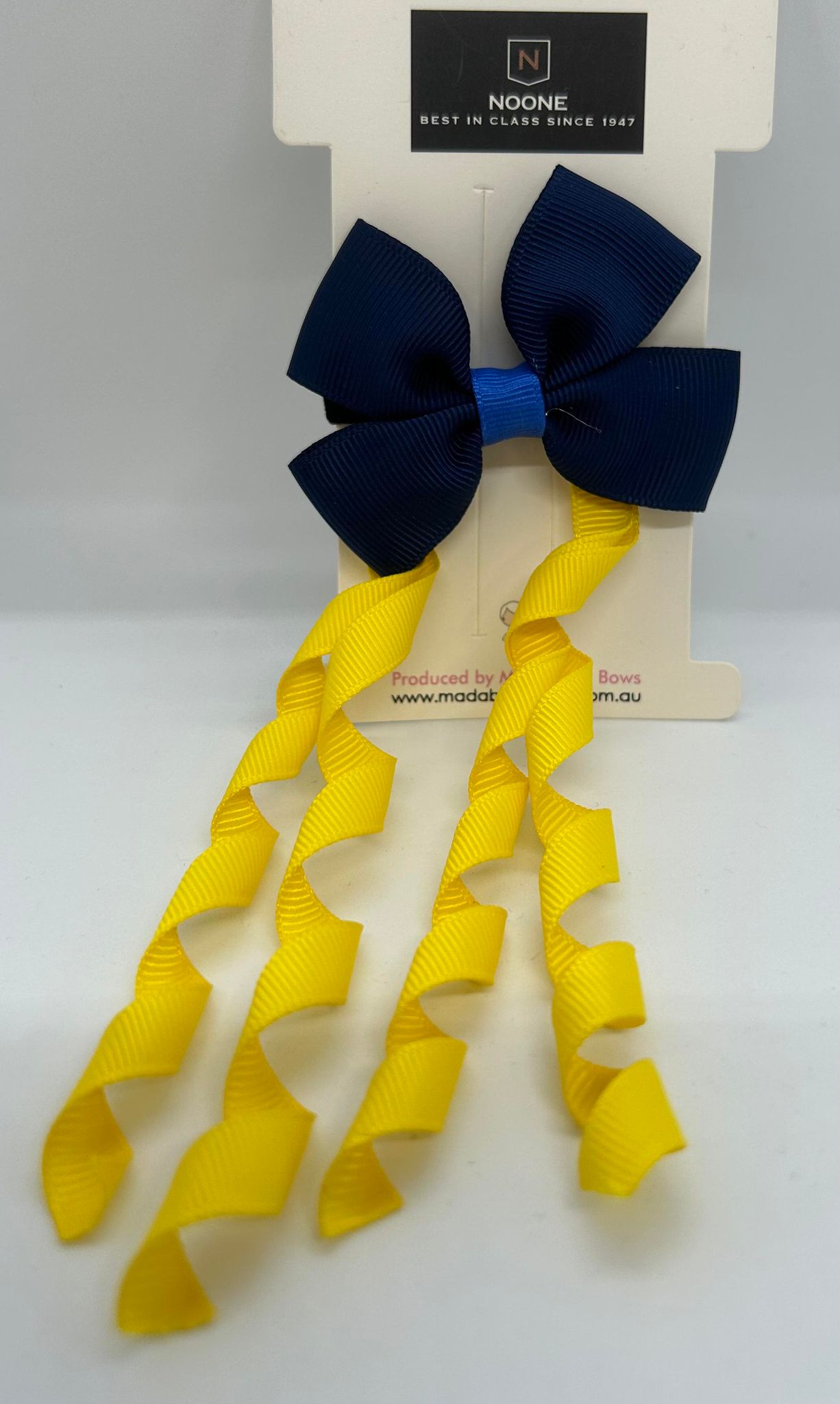 a hair bow that is navy blue with curly light yellow tails