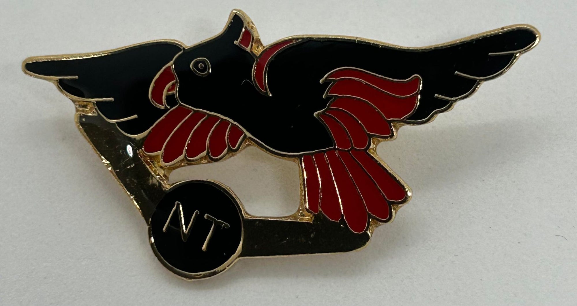 a metal badge with an enamel front with the NT fauna emblem in black and red
