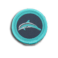 a round dark blue badge bound in teal with a dolphin on it
