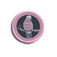 a round badge bound in pink with a pink galah on it