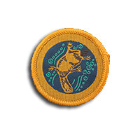 a round badge bound in gold with a platypus on it