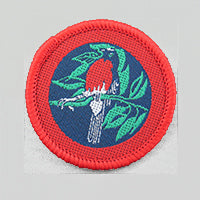 a round badge bound in red with a red robin on it