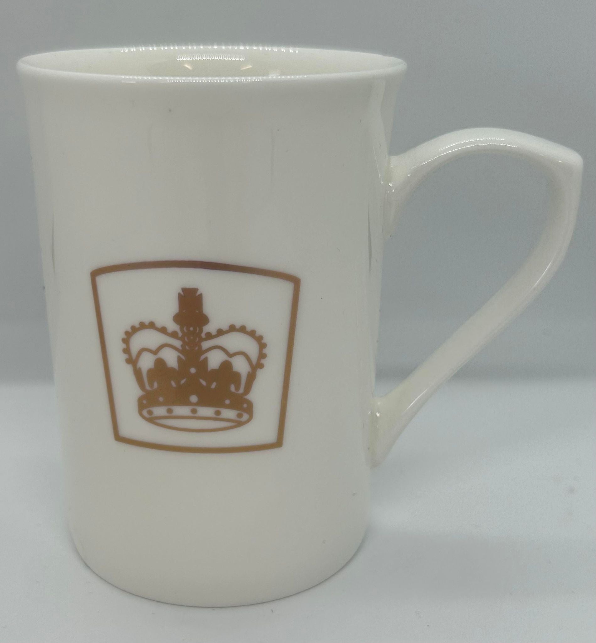 a white coffee cup with a gold crown on the side