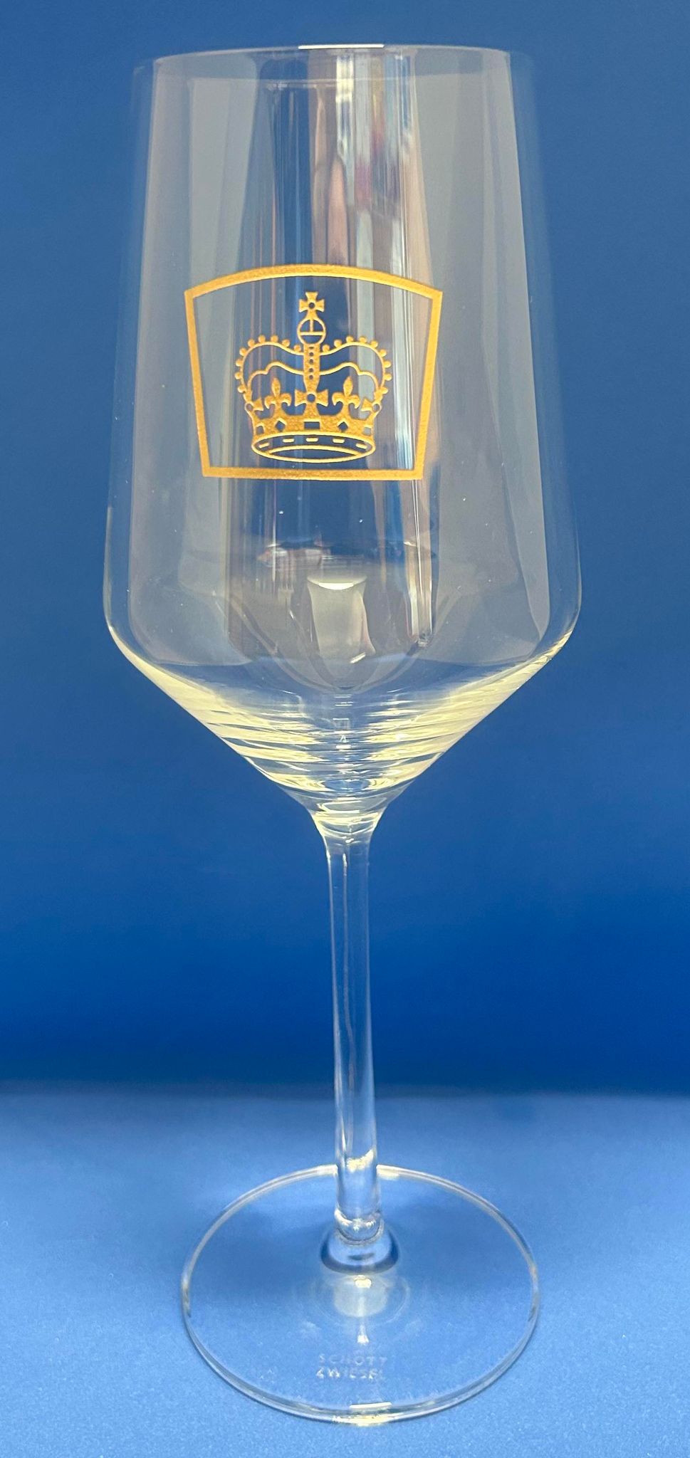 a wine glass with the queens guide emblem etched in gold