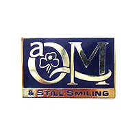 a rectangle shaped blue and silver badge that says QM & still smiling
