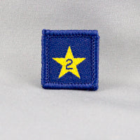 square blue badge with a gold star with the number two in the centre written in blue