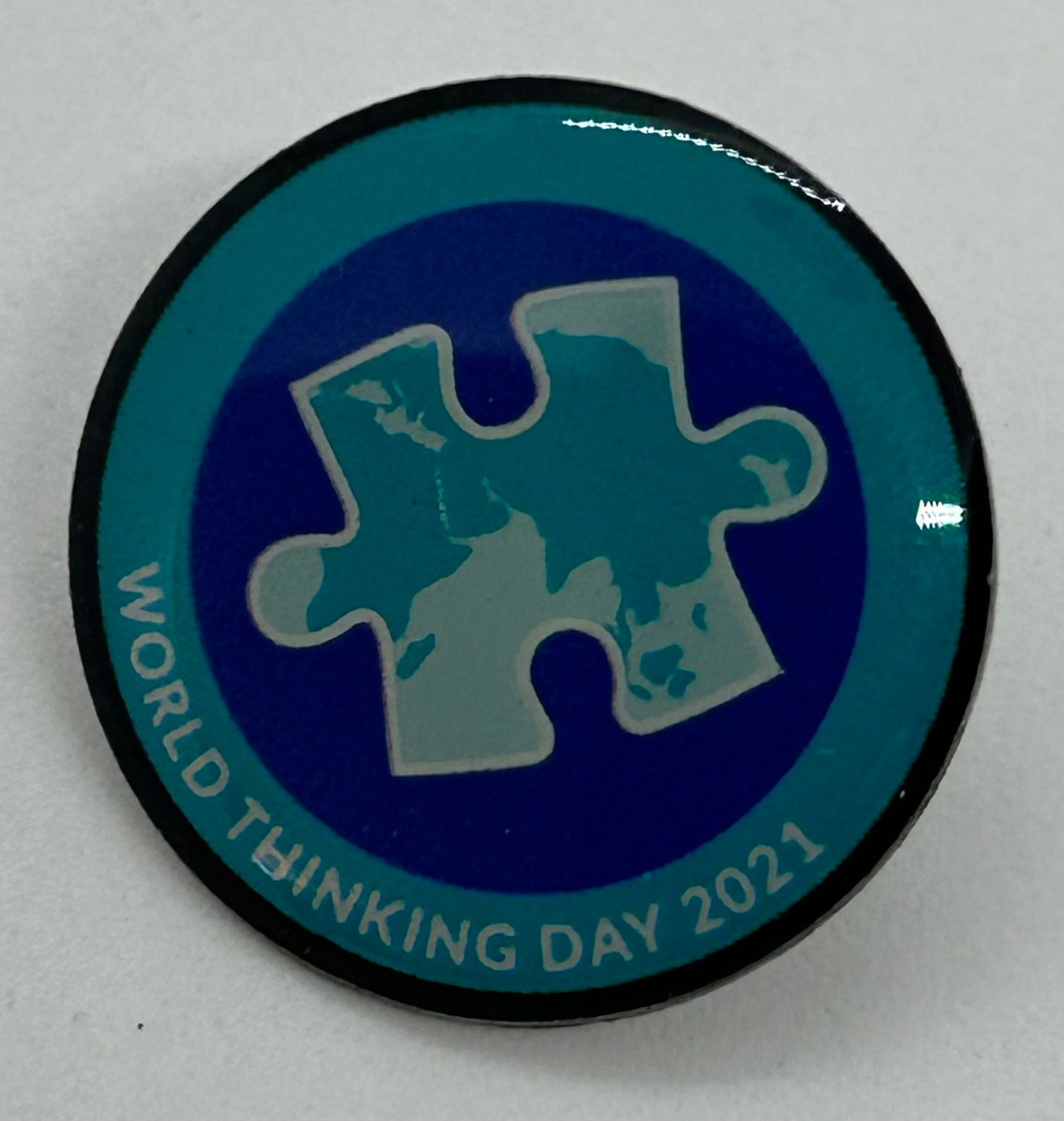 a metal badge with a blue enamel front with a jigsaw piece on the front