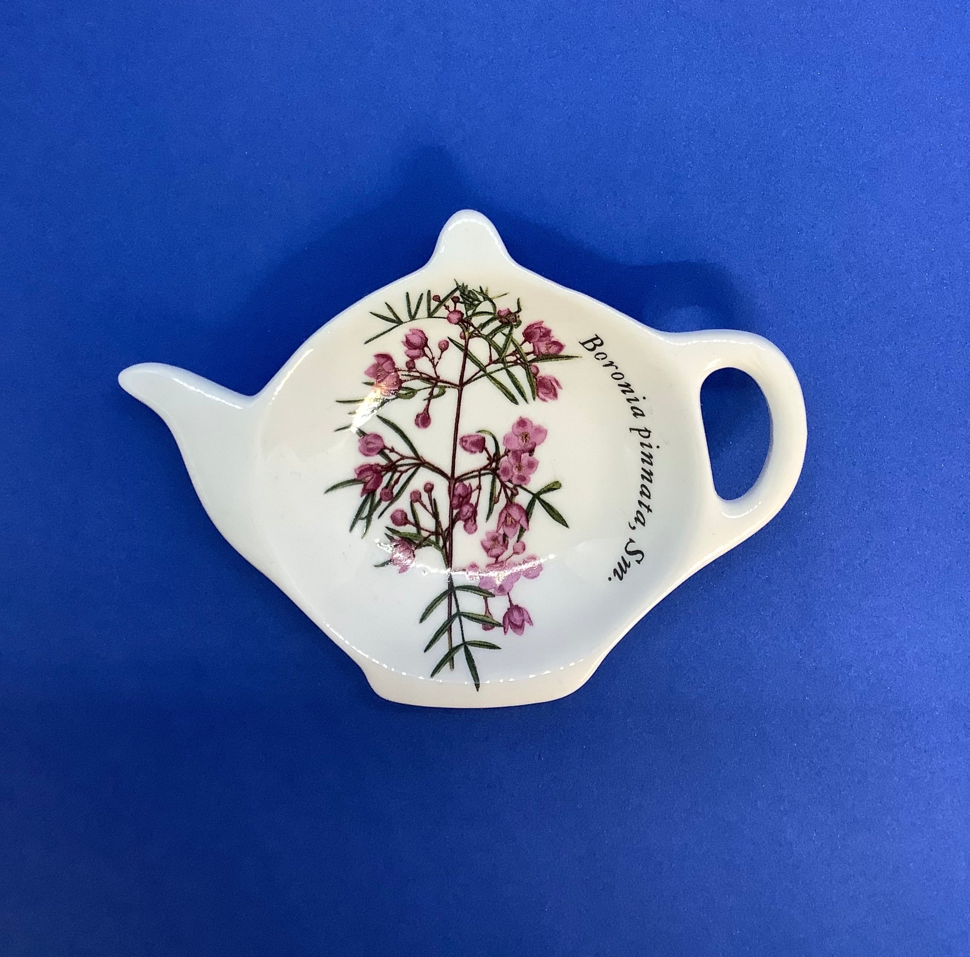 a white tea bag tidy with pink boronia flowers shaped in the shaped of a teapot