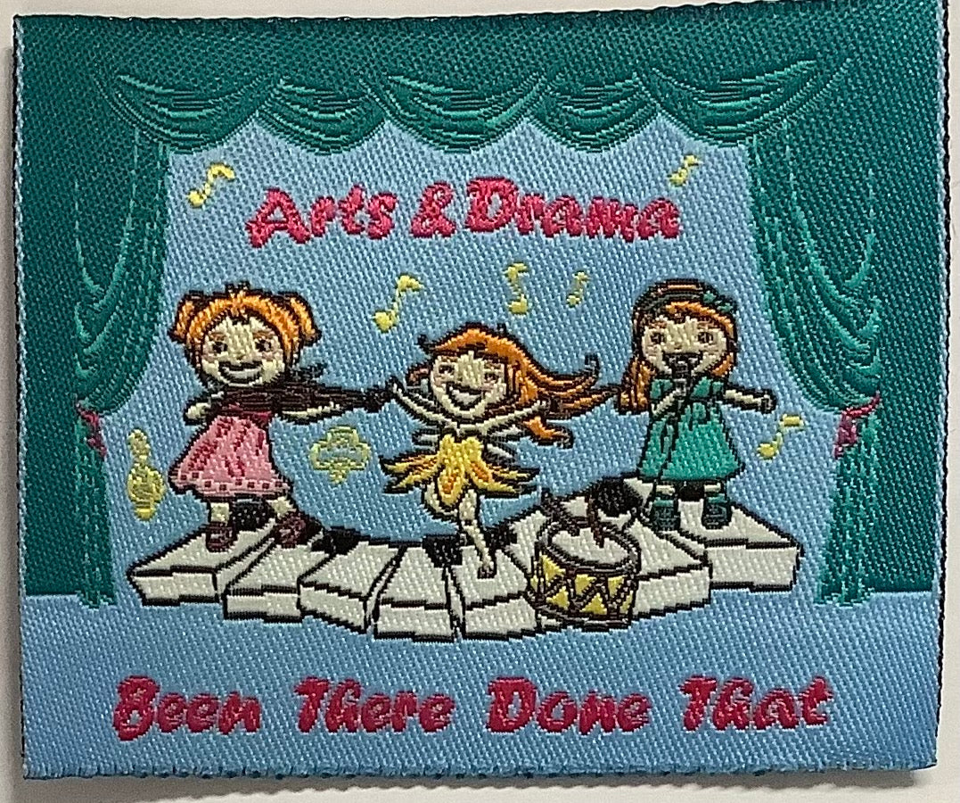 a square unbound badge with three girls singing and dancing on giant piano keys