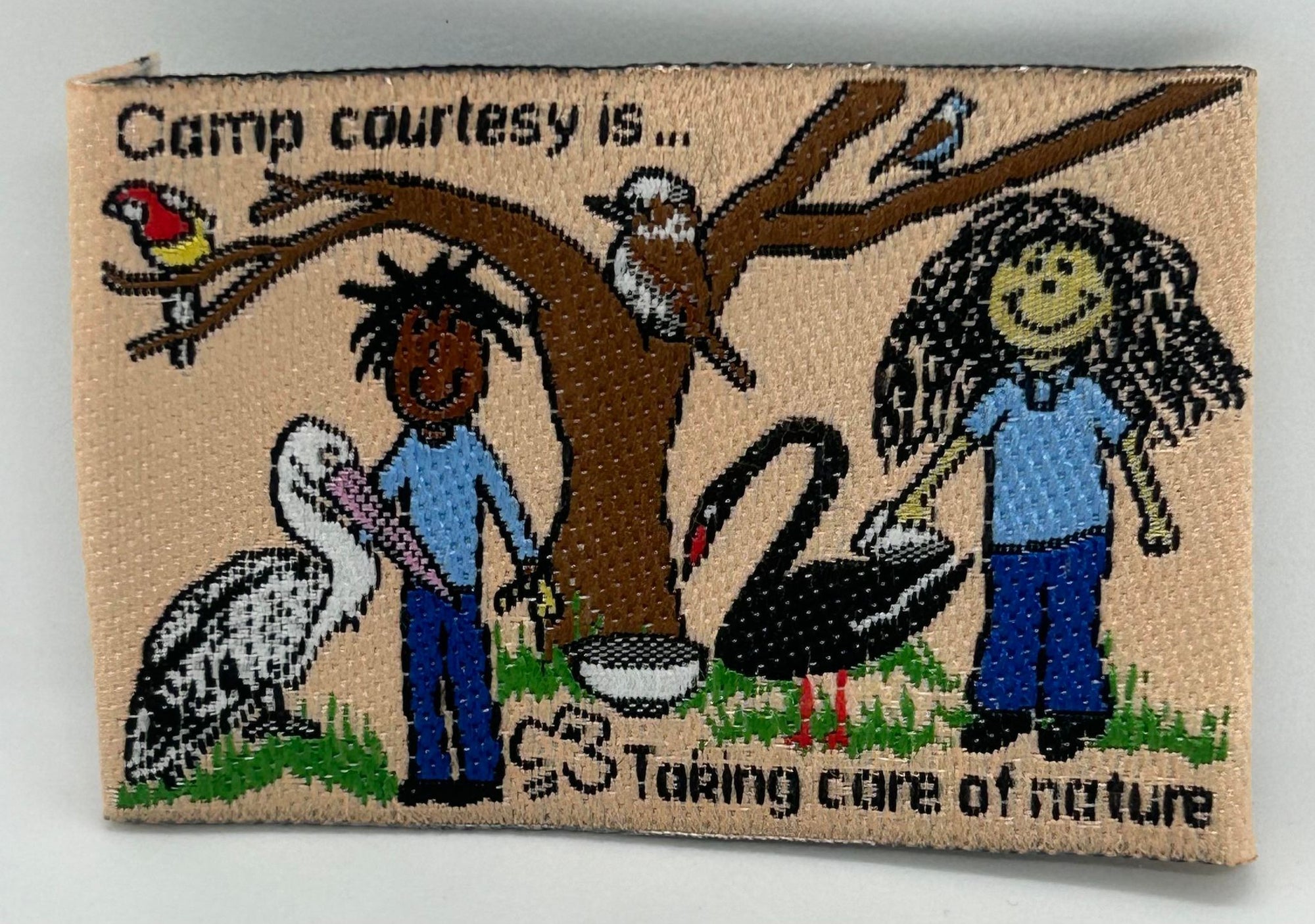 a rectangular unbound badge with two girls, a tree and animals on it