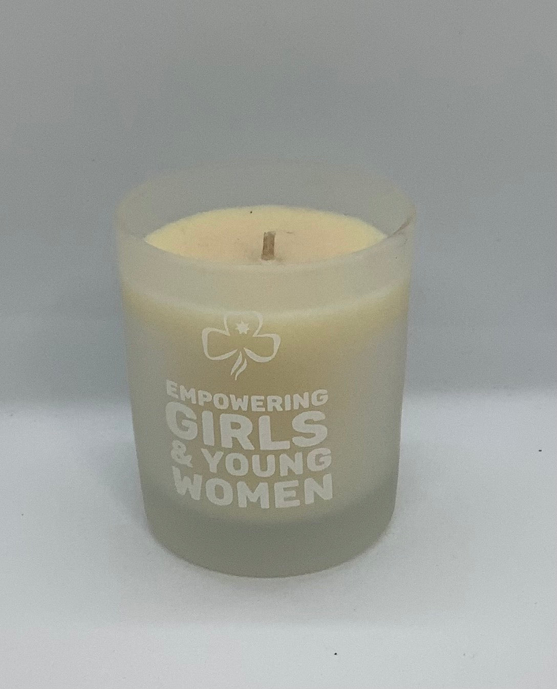 a candle in a small jar with empowering girls & young women on the front