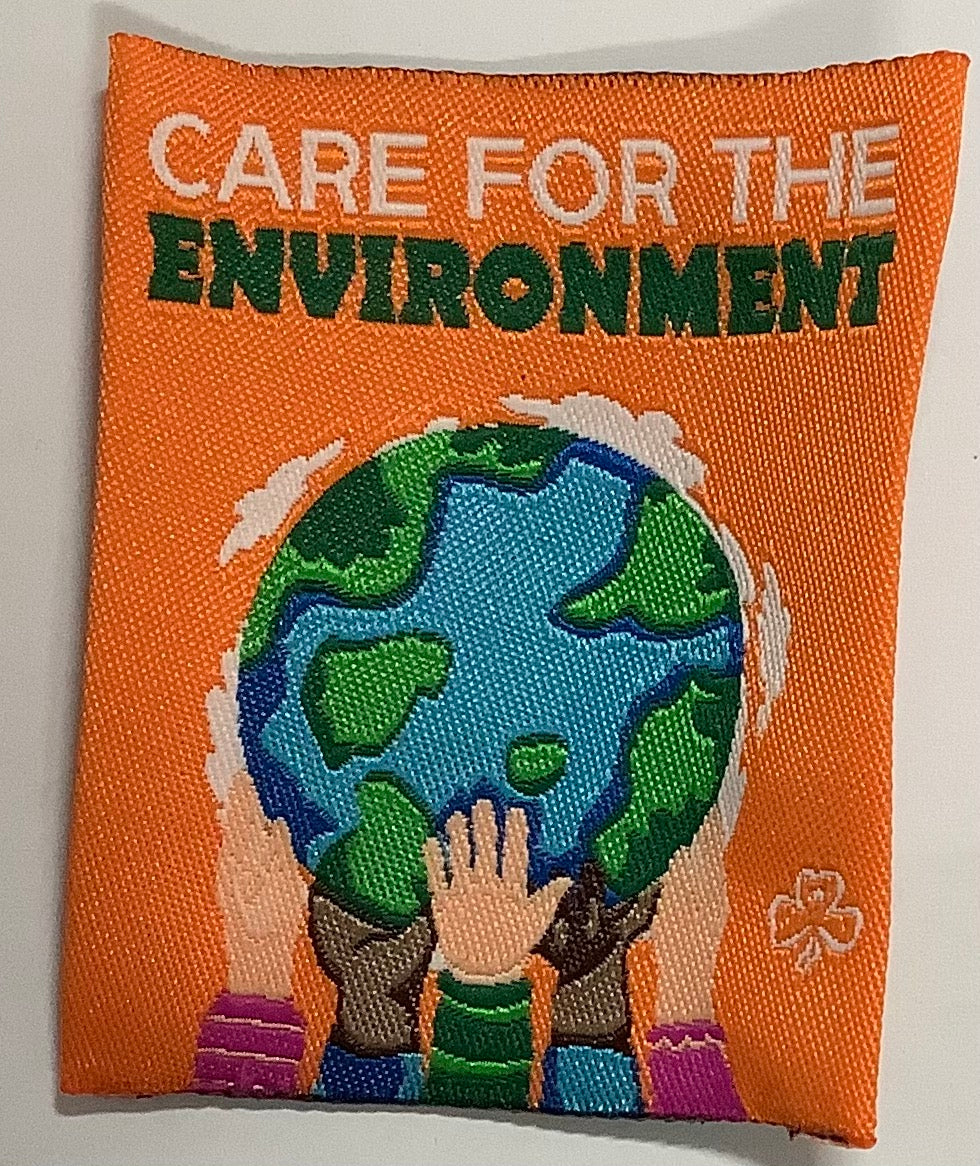 a square unbound badge that is orange with four hands holding up a globe