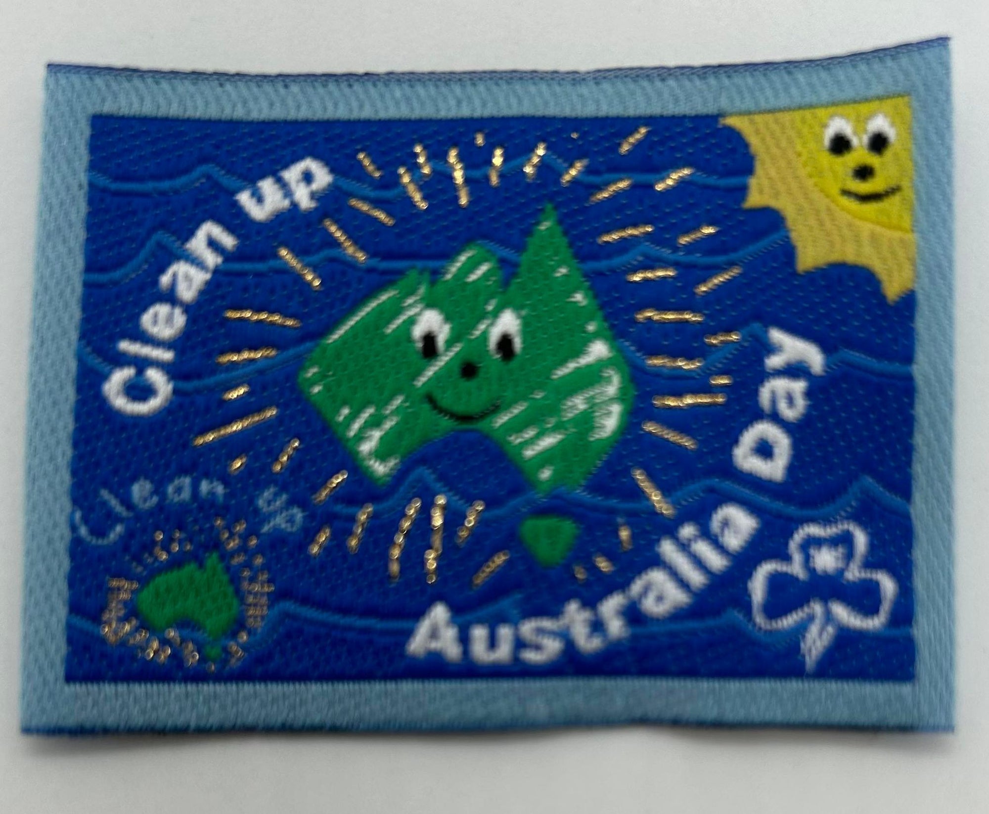 a square unbound woven badge with clean up Australia written on it with light blue around the edges and a green map of Australia in the middle