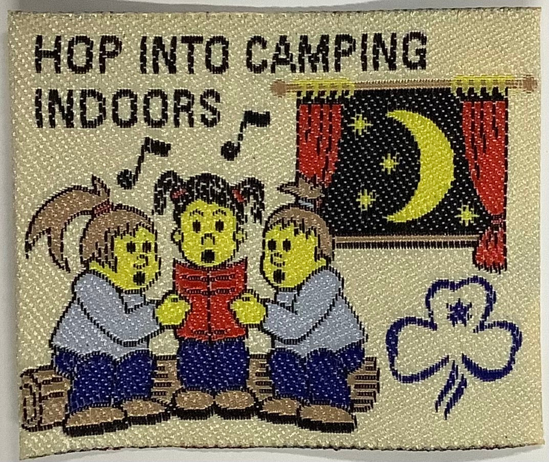 a square unbound badge with three guides sitting on a log singing
