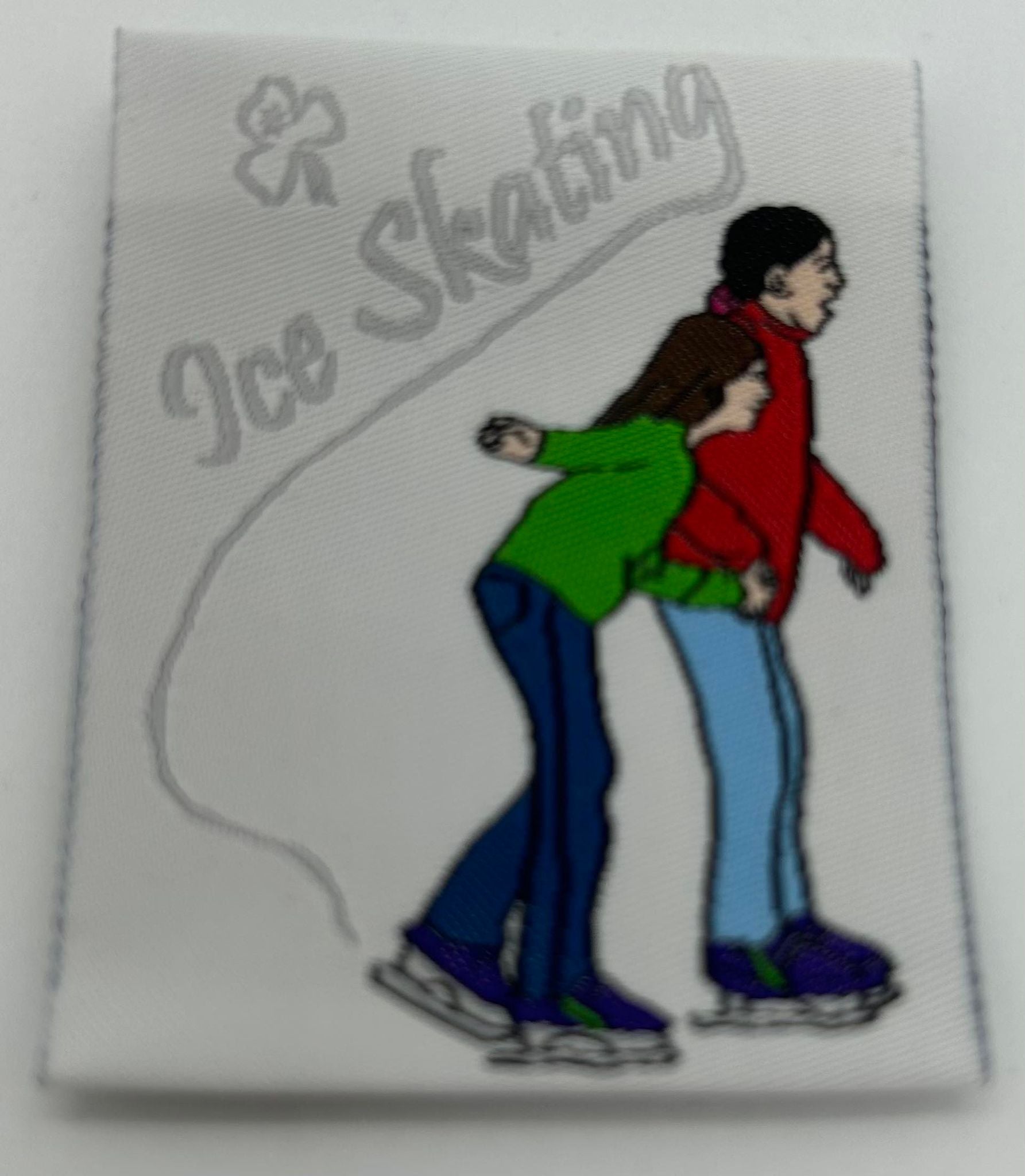 a square unbound woven badge with two people ice skating