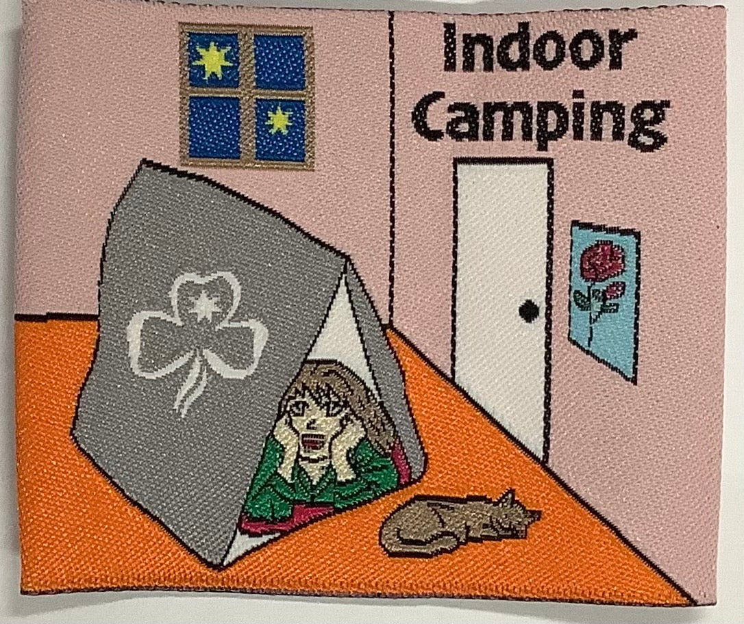 a square unbound fun badge with a girl in a tent indoors