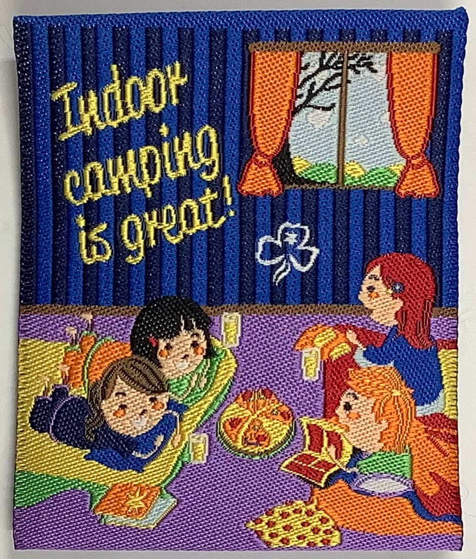 a square unbound fun badge with girls camping on the floor while talking and eating