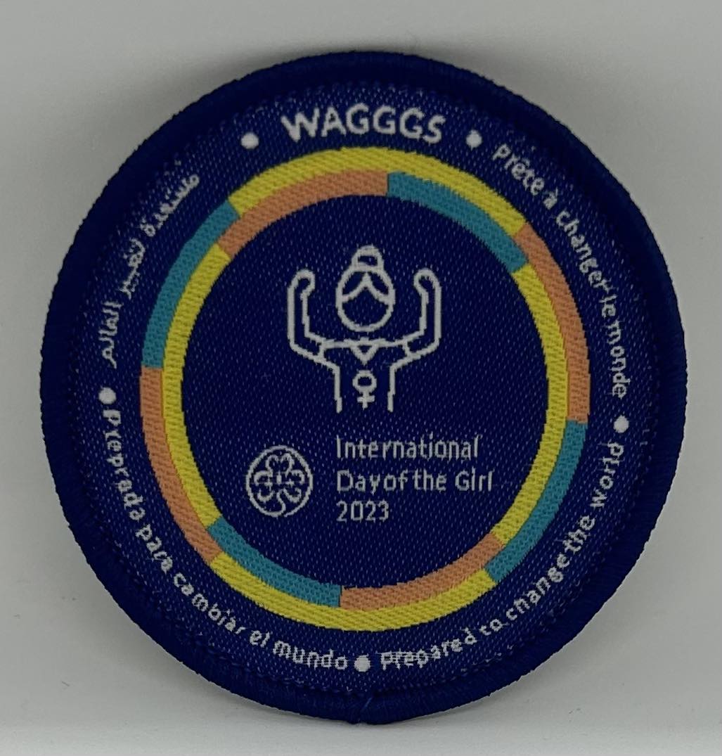 a round blue bound badge celebrating international day of the girl with a cartoon of a girl in the centre