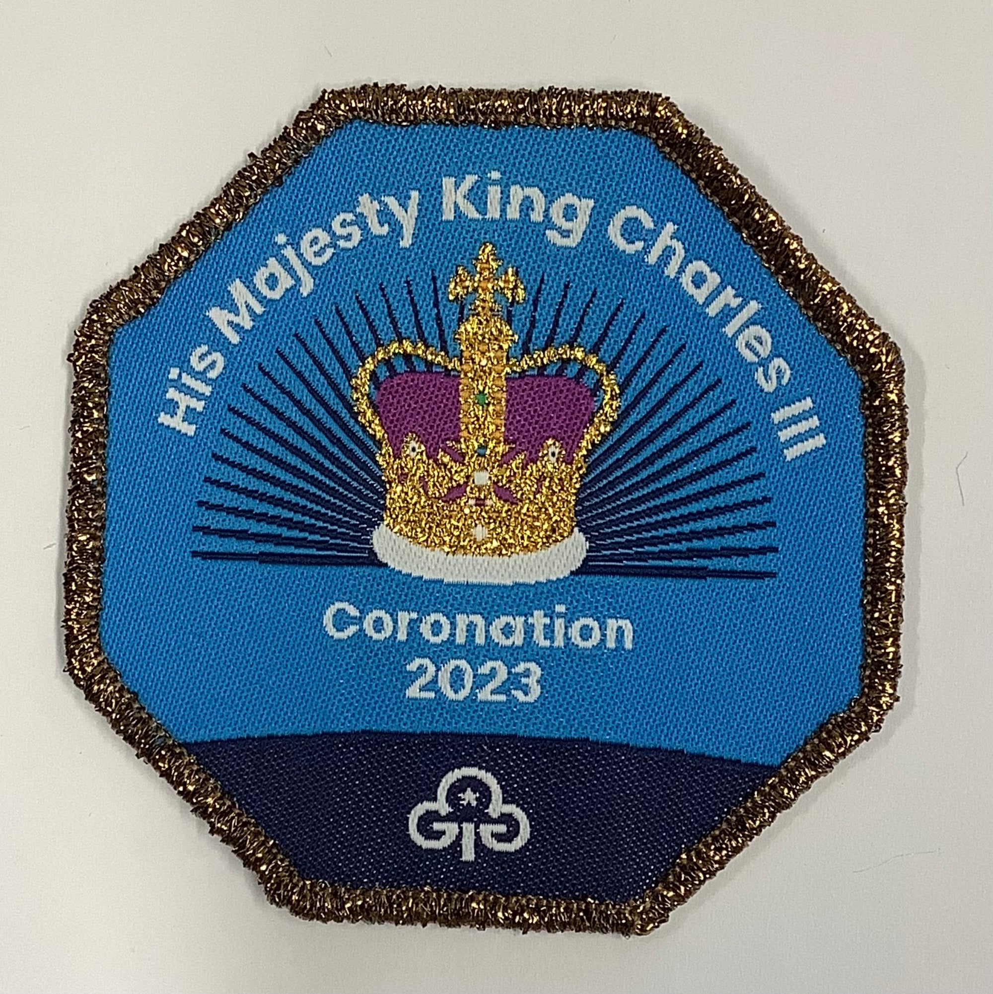 a octagon shaped badge bound in gold with the crown for the kings coronation