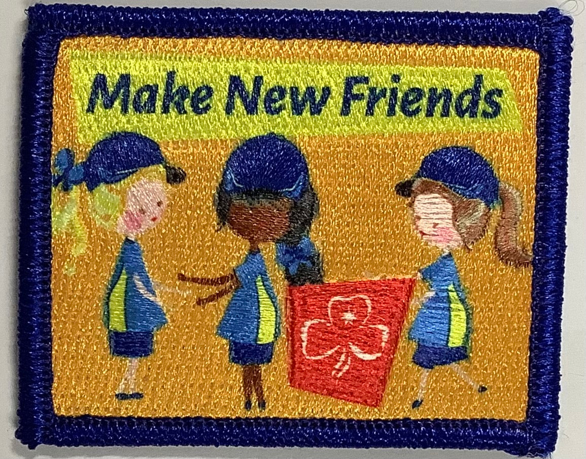 a square badge bound in blue with three junior guides making friends