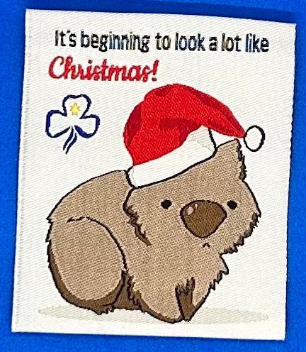 a square unbound badge with a wombat with a Santa hat on
