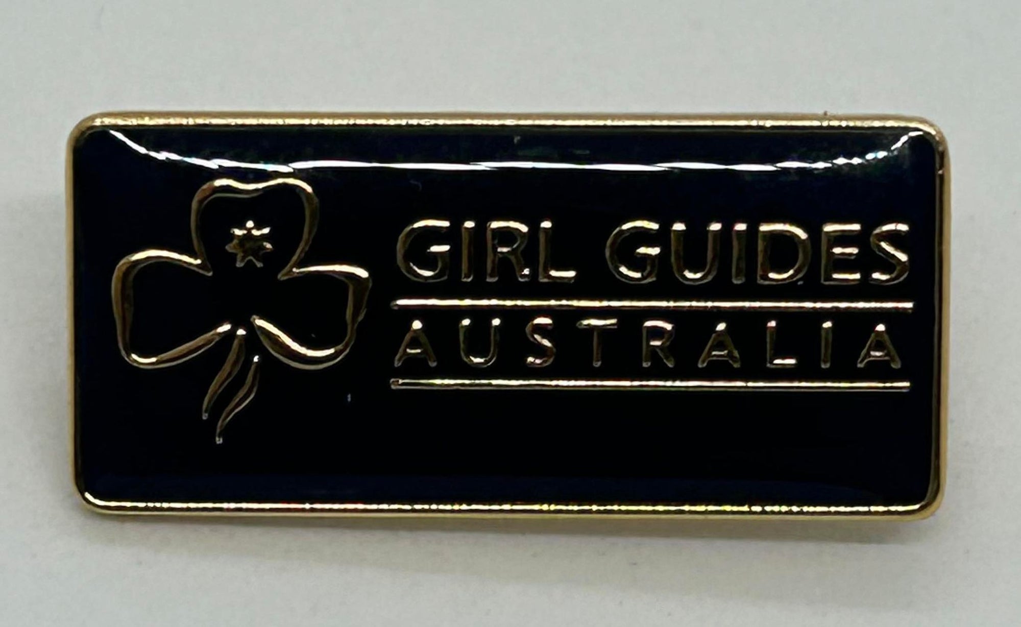 a mini metal pin with a navy blue enamel front with the trefoil and girl guides Australia in gold