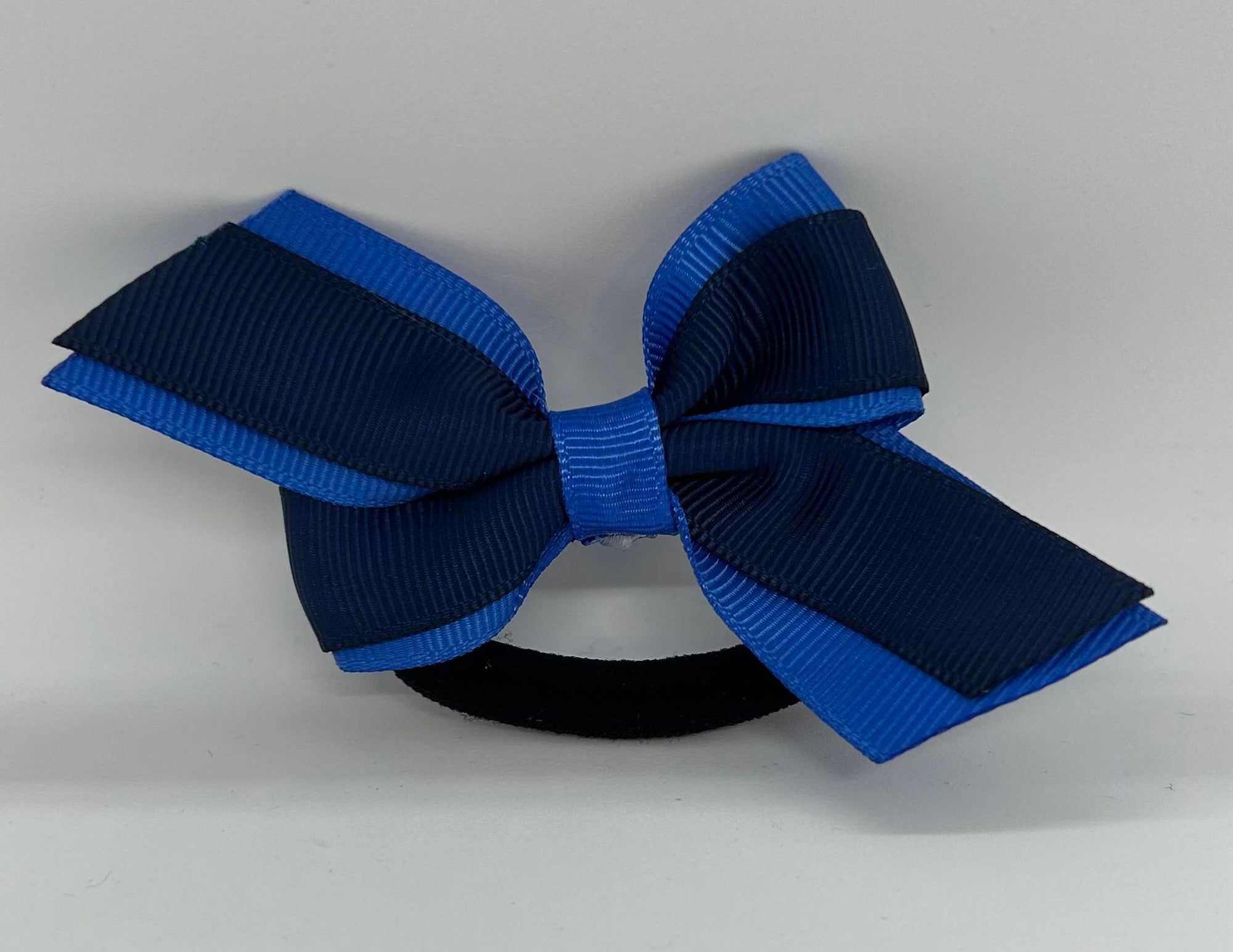 a navy and blue hair bow on a hair tie