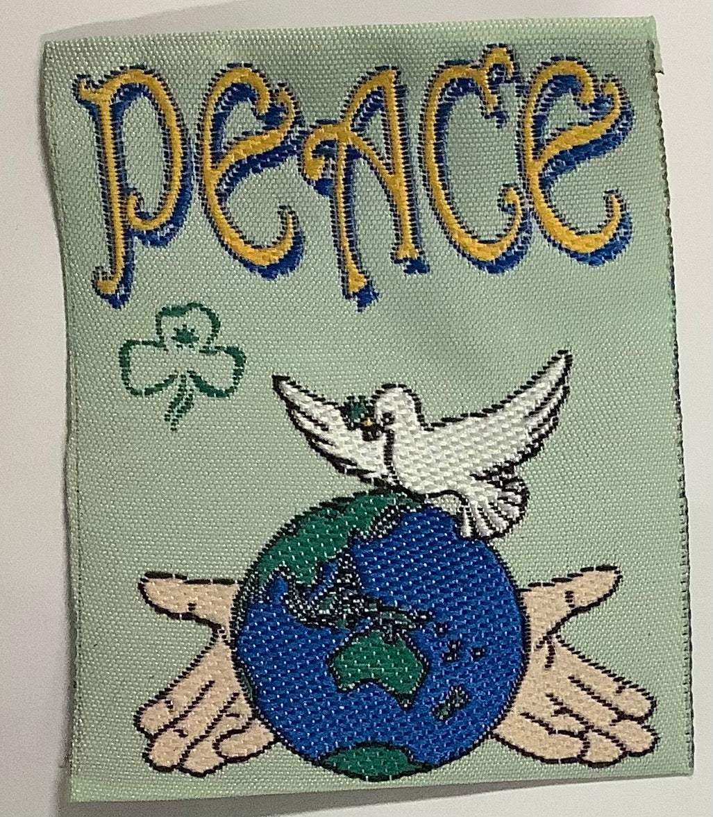a square unbound badge with a dove and a globe being held in hands