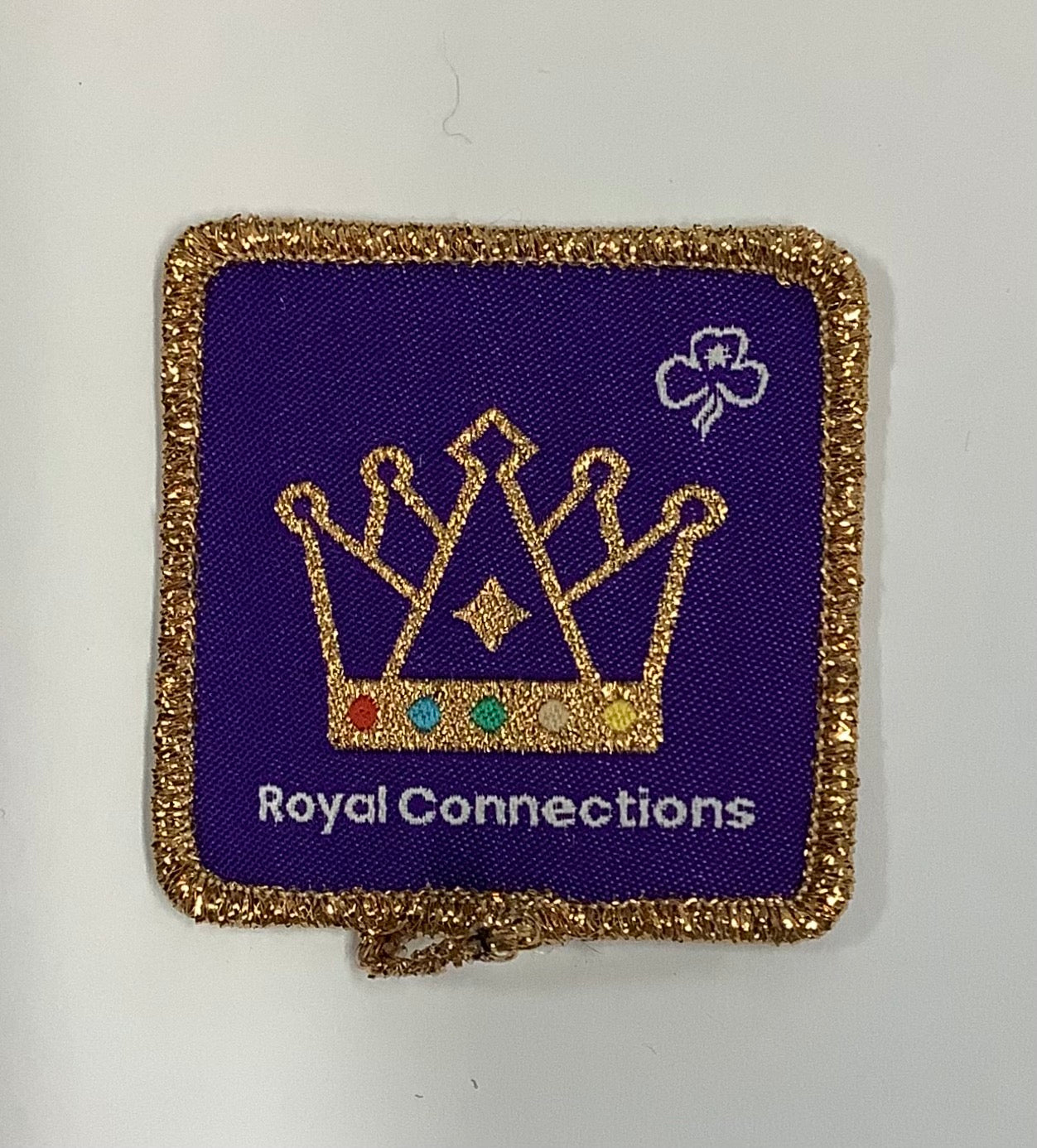 a square purple badge bound in gold with a gold crown