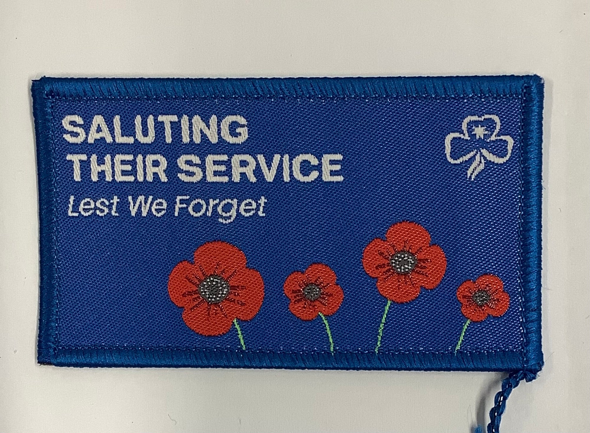 a rectangular blue badge bound in blue with red poppies 