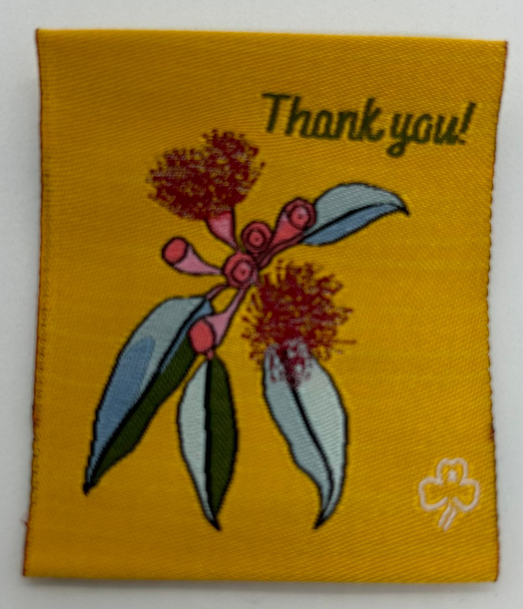 a square gold unbound fun badge with a flowering gum and the words thank you