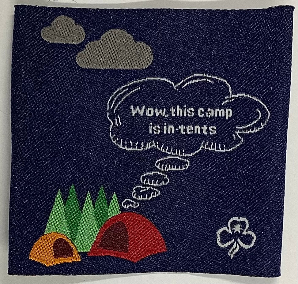 a square unbound blue badge with tents and trees