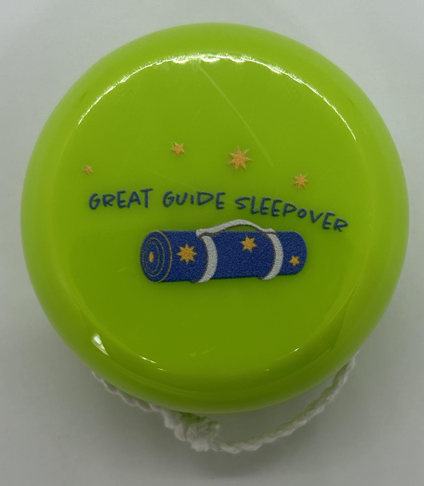 a green plastic yoyo with grey guide sleepover and logo on the front