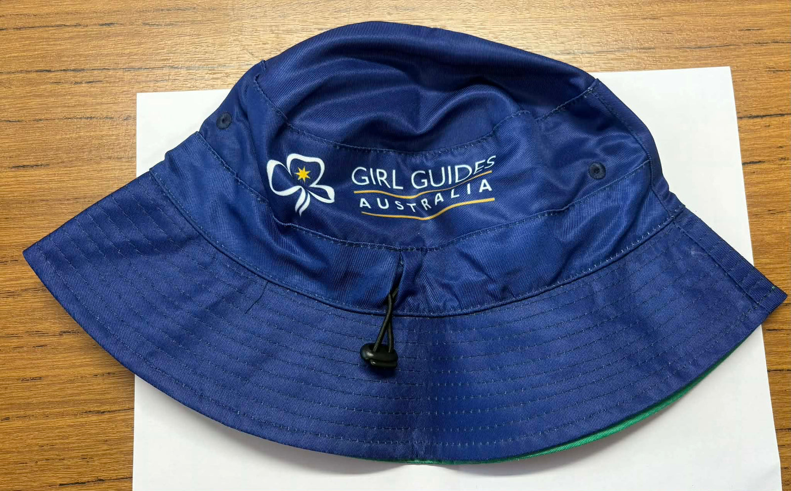 Blue bucket hat with Girl Guides Australia logo with a green reversible side with a kangaroo and dolphin pattern